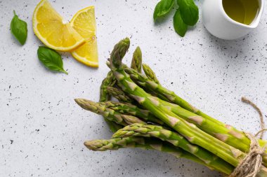 Beyaz arka planda seçici odak, yeşil kuşkonmaz kapsülleri. Limon dilimleri, baharatlar ve fesleğenli.