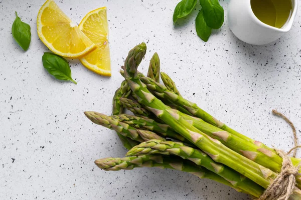 Beyaz arka planda seçici odak, yeşil kuşkonmaz kapsülleri. Limon dilimleri, baharatlar ve fesleğenli.
