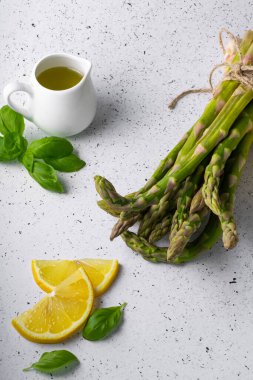 Beyaz arka planda seçici odak, yeşil kuşkonmaz kapsülleri. Limon dilimleri, baharatlar ve fesleğenli.