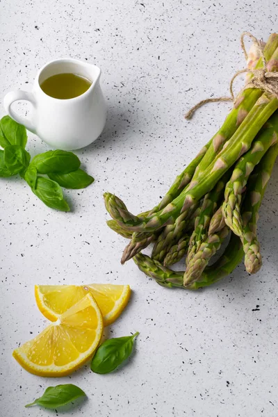 Beyaz arka planda seçici odak, yeşil kuşkonmaz kapsülleri. Limon dilimleri, baharatlar ve fesleğenli.