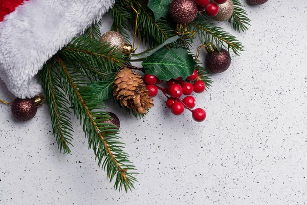 Seçici odaklanma. Noel ışığı düzeni, ağaç dalları ve kırmızı yumuşak bir Noel şapkasıyla süslemeler.