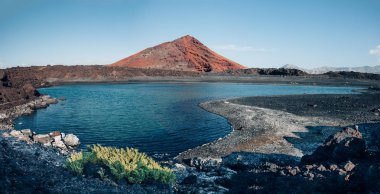 Panoramic view of unique volcanic landscape in Lanzarote island. Black sand, lake and and red mountain. Playa Bermeja. Travel destination. Nature background. unesco heritage. Canary Islands clipart
