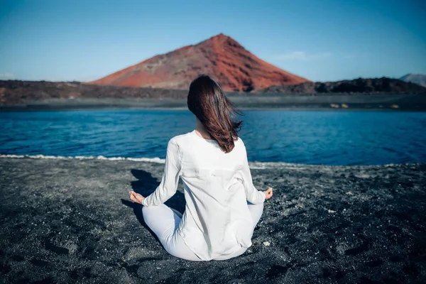 若い女性は ロータスはユニークな黒砂ビーチ プラヤ Bermeja ランサローテ島 カナリア諸島 スペインのポーズで瞑想します Padmasana コンセプトをリラックスします — ストック写真