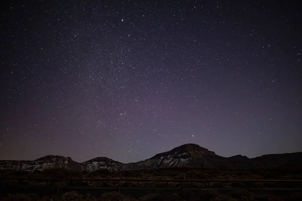 Night sky with shiny stars above mountain Roques de Garcia stone. Milky Way.  Night in the Teide National Park, Tenerife, Canary Islands, Spain. Space background