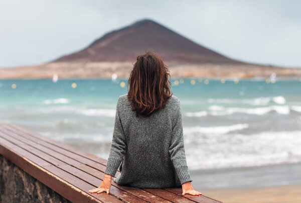 Back view of young woman enjoy the ocean. Relax concept. Fuerteventura, Canary islands, Spain. 