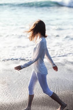 Beyaz giysili sahilde yürüyen mutlu kadın. Özgürlük kavramı