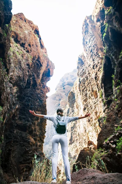 Happy traveler woman with raised arms enjoying fantastic view of mountains range in Masca Gorge, Canary Islands, Spain. Travel destination. Success concep