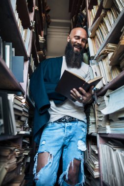 Mutlu gülümseyen adam okuma kitabı kitap rafı arka planda.