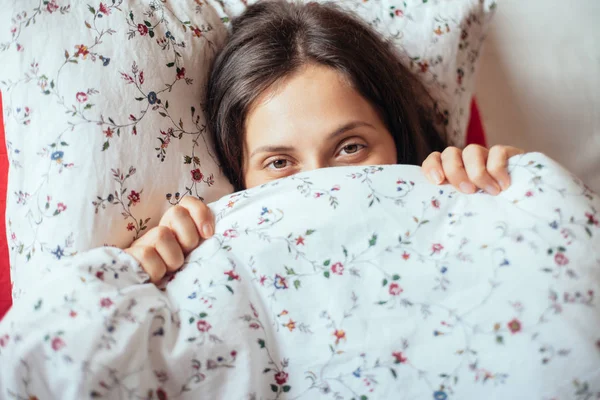 クローズ アップのベッドで毛布の下探している若い女性 女性の隠れ顔 — ストック写真
