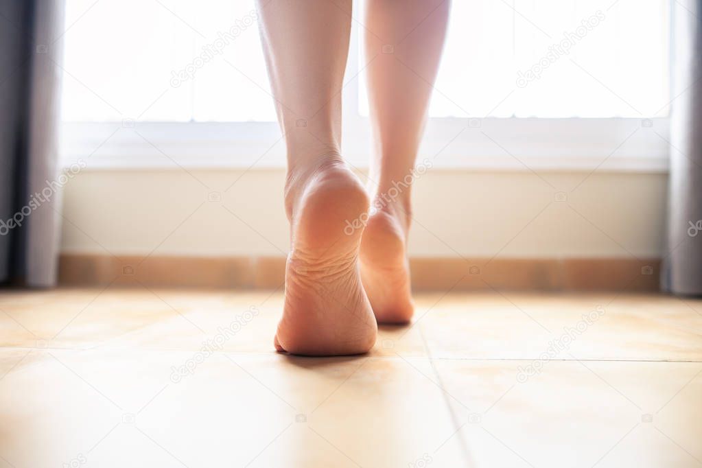 Woman bare feet walking on floor, closeup.