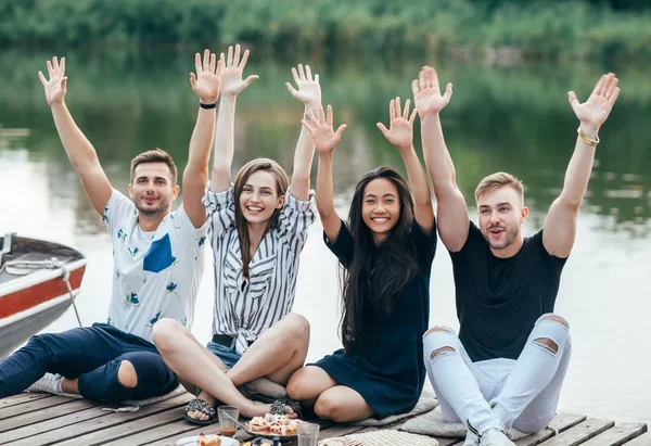 快乐的朋友举起手放松在户外野餐在河上 — 图库照片