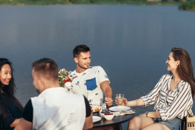 Yemek ve having fun nehir kıyısındaki restoranda genç arkadaşlar.