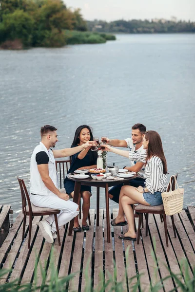 Grupo Jóvenes Amigos Comiendo Divirtiéndose Restaurante Aire Libre Junto Río —  Fotos de Stock