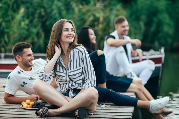 Jóvenes Amigos Sonriendo Mientras Relajan Muelle Del Río Sentado Fila —  Fotos de Stock