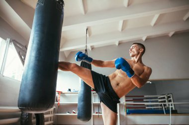 Erkek boxer egzersiz yüksek tekme üzerinde kum torbası içinde jimnastik salonu. Spor kavramı 
