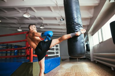 Erkek boxer egzersiz yüksek tekme üzerinde kum torbası içinde jimnastik salonu. Spor kavramı 