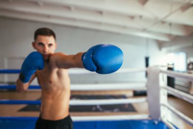 Erkek boxer spor salonunda mücadele ve direk vuruş yapma. Boks eldiveni üzerinde odaklanın. Spor kavramı