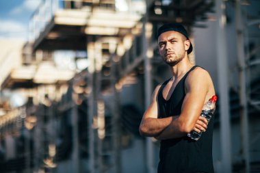 Endüstriyel zemin üzerine poz ciddi yakışıklı adam elinde şişe su tutun