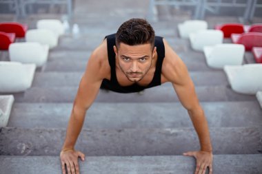 Ciddi adam Stadyumu merdivenlerde şınav. Üstten görünüm. Fitness, spor, kas egzersiz 