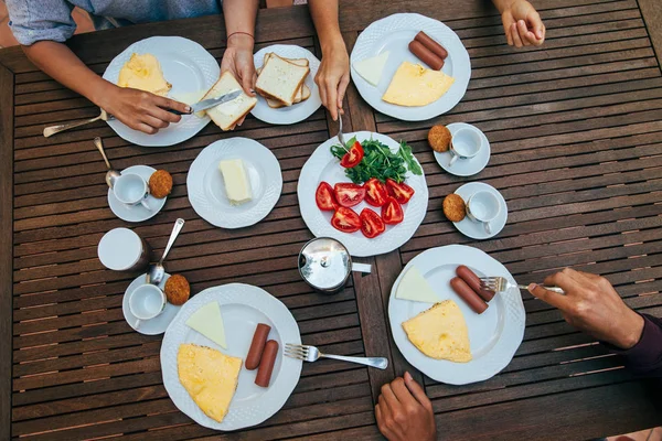 Enjoying breakfast with friends. Top view of group of people having meal together while sitting at the rustic wooden table