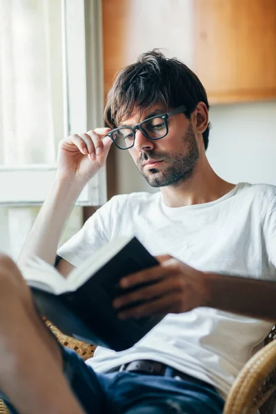 Jovem Homem Bonito Óculos Leitura Livro Sentado Cadeira Casa — Fotografia de Stock