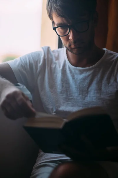 Młody Przystojny Mężczyzna Okularach Czytanie Książki Posiedzeniu Pobliżu Okna Koncepcja — Zdjęcie stockowe