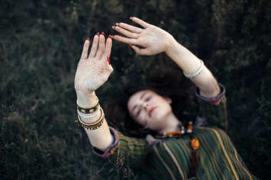 Elleriyle çim üzerinde yalan güzel boho kız. Yandan odaklanmak