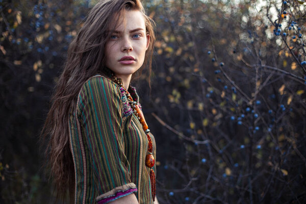 Fashion portrait of young boho girl at sunset posing on nature background