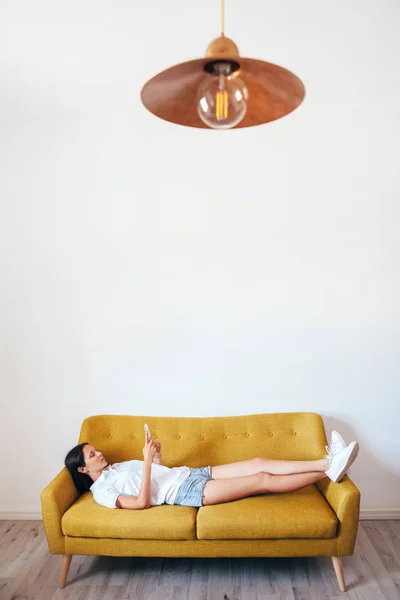 Χαλαρή Γυναίκα Χρησιμοποιώντας Ένα Smartphone Ξαπλωμένη Στο Κρεβάτι Στο Σπίτι — Φωτογραφία Αρχείου