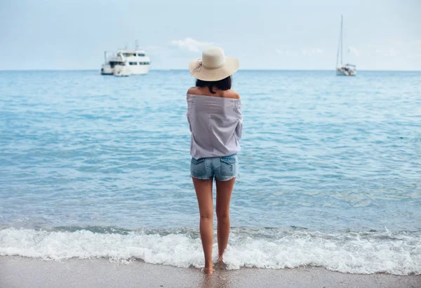 帽子の若い女性の背面図は 夏休みに海とビーチからボートをお楽しみください — ストック写真