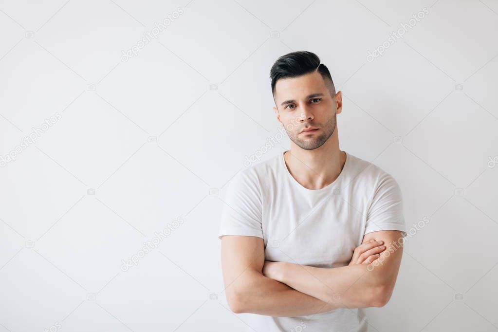 Confident handsome man with crossed arms on white background and copy space