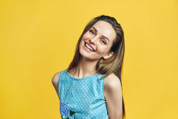 Portrait of beautiful smiling woman looking in camera on yellow background