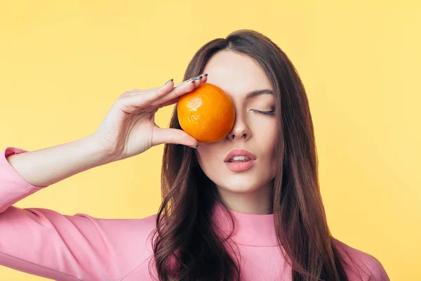 Mulher Bonita Segurando Laranja Frente Olho Fundo Amarelo Conceito Alimentação — Fotografia de Stock