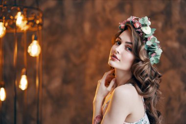 Saçında çiçek çelengi olan genç bir kadın. Moda portresi                        