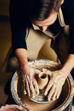 Çömlekçilik atölyesinde kilden seramik çömlek yapan çömlekçi çarkı üzerinde çalışan adam çömlekçi. sanat kavramı