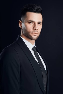 Koyu renkli siyah takım elbiseli yakışıklı kendine güvenen bir adam. Erkek güzelliği                              