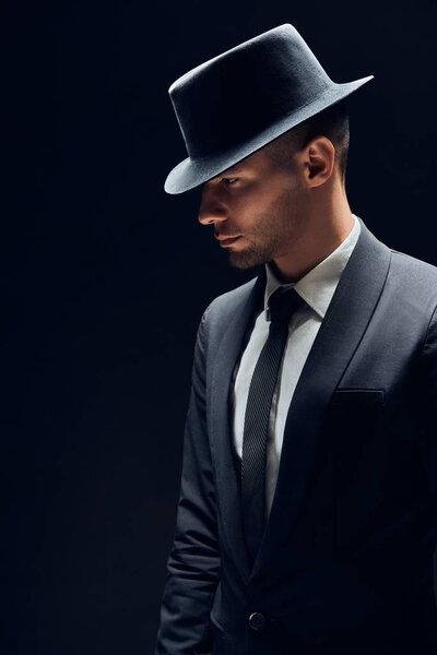 Profile view portrait oh handsome man in black suit and hat on dark background. Man beauty concept                                         
