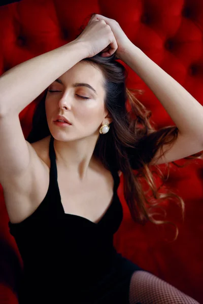 Zmysłowy Piękna Kobieta Pozowanie Seksownej Czarnej Sukni Czerwonej Kanapie Kobiece — Zdjęcie stockowe