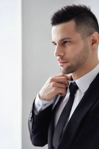 Young Handsome Man Elegant Suit Adjust His Necktie White Background — Stok fotoğraf