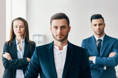 Arka planda ekibi ile ofiste emin yakışıklı işadamı portresi. Liderlik ve başarı konsepti