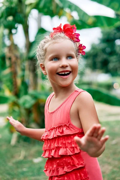 赤い花と夏の庭でかわいい笑顔の小さな女の子の肖像画 — ストック写真
