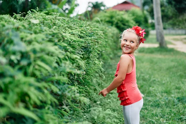 可爱的微笑小女孩肖像在夏天的花园与红花 — 图库照片