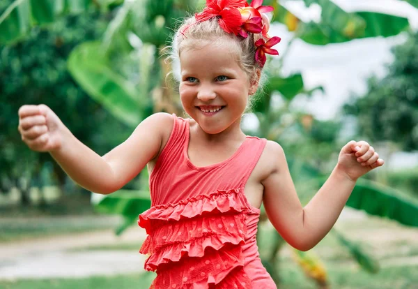 赤い花で夏の庭で踊るかわいい笑顔の女の子 — ストック写真