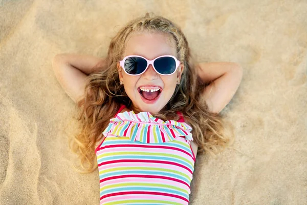 夏休み中に砂浜に横たわっているサングラスのかわいいブロンドの女の子のトップビュー — ストック写真