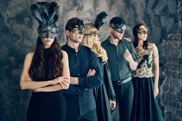 仮面舞踏会のカーニバルマスクを着た若者のグループがスタジオでポーズをとり 列に並ぶ ファッション写真コンセプト — ストック写真