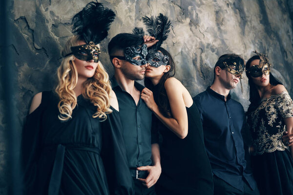 Group of young people in masquerade carnival masks posing in studio. Fashion photo concept.                