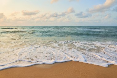 Sörf dalgaları ve bulutlu gökyüzü ile Plaj