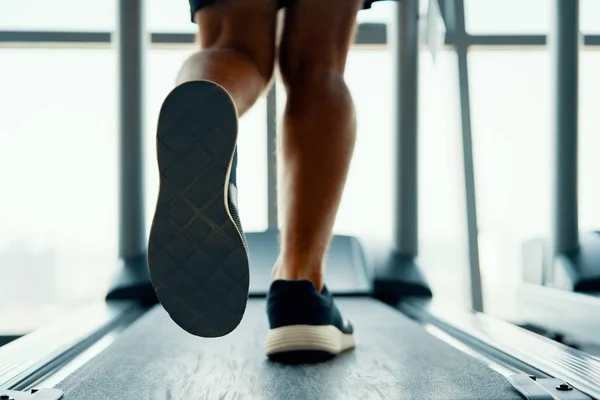 特写男性肌肉脚在运动鞋运行在跑步机在健身房 — 图库照片