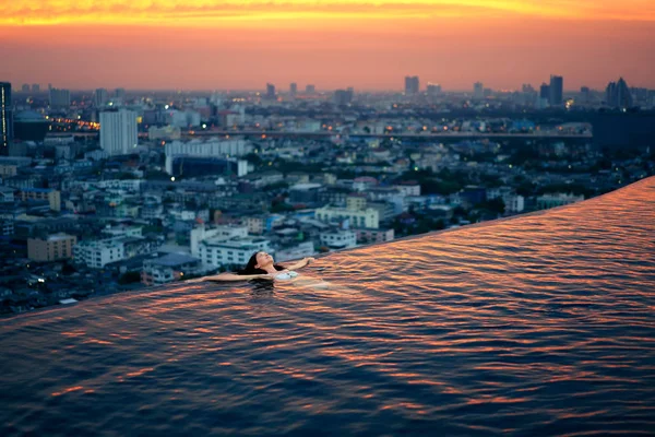 Young woman relaxing in swimming pool on rooftop during amazing sunset — Stock Image Young Woman Relaxing Swimming Pool Rooftop Amazing Sunset Royalty Free Stock Photos