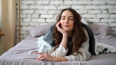 Genç ve zarif kadın yatakta poz veriyor.